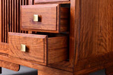 Photograph of newly remodeled cabinets. The cabinets are made of red wood and have brass handles on cabinet doors.